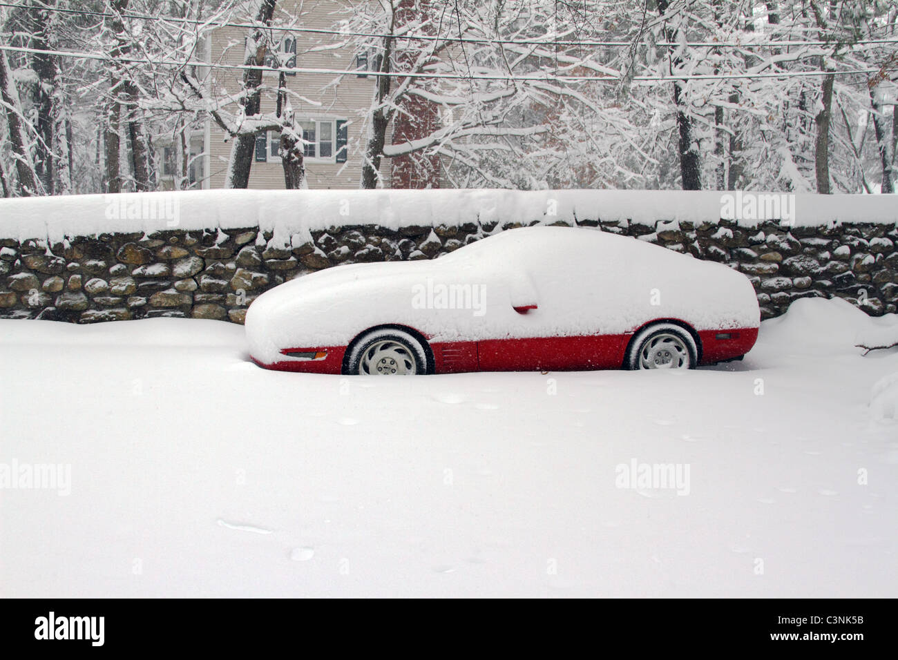 Red Corvette si siede nella neve, in attesa di insorgenza di New England molla Foto Stock