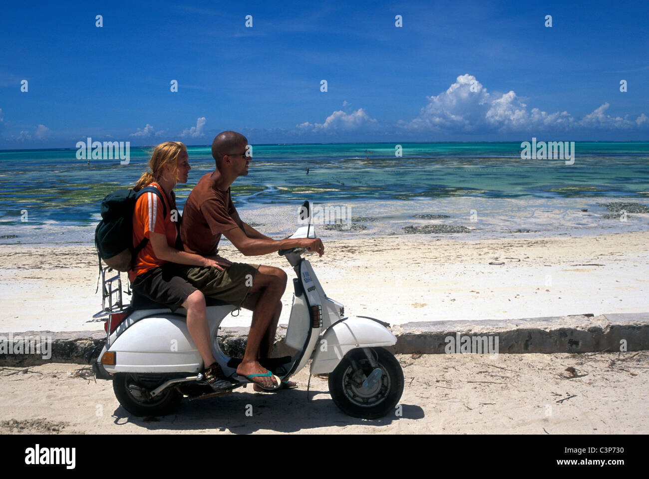 Un ragazzo e una ragazza in sella scooter lungo la costa est di Zanzibar Foto Stock