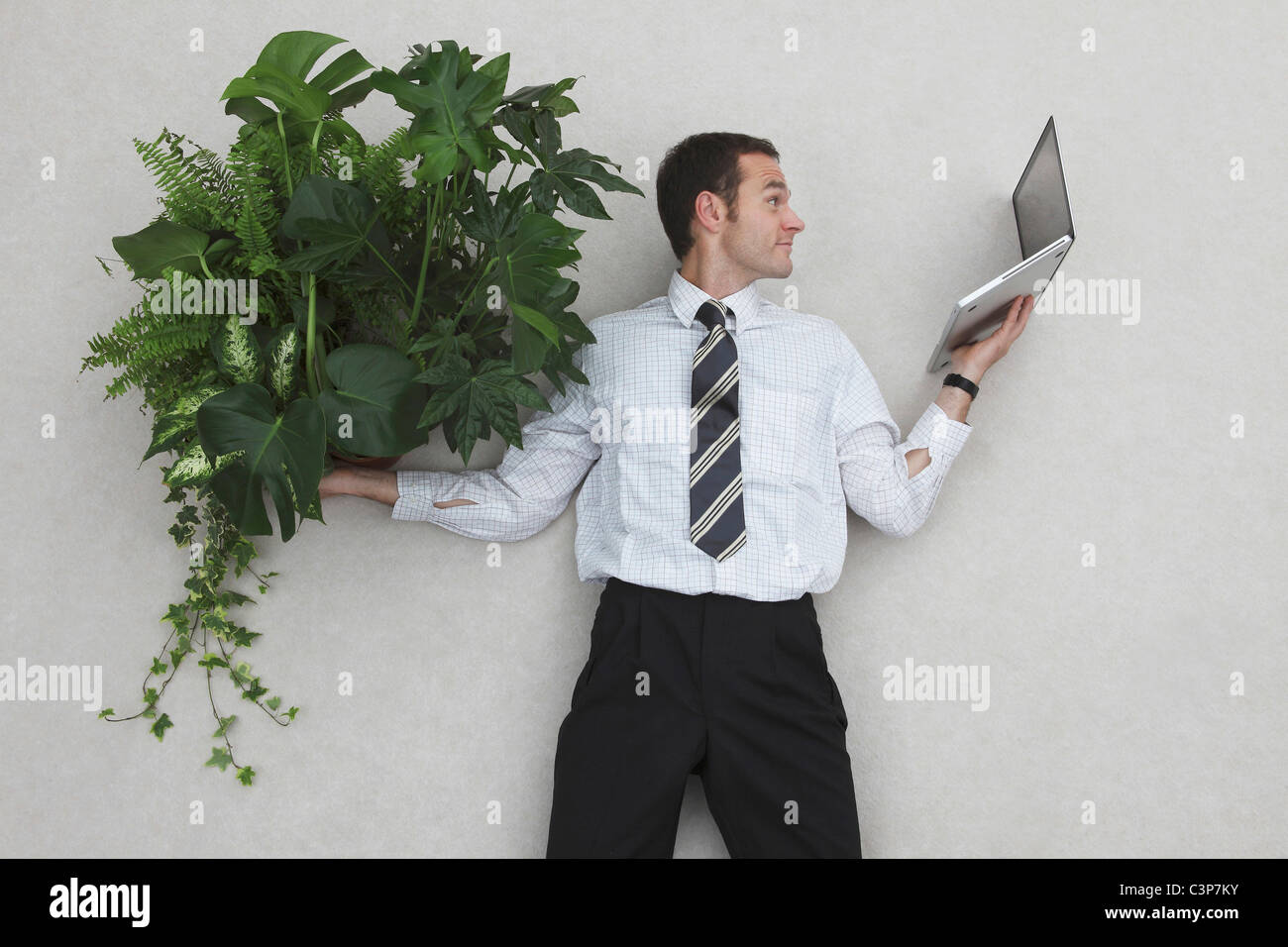 Imprenditore azienda laptop e foglie di piante, ritratto Foto Stock