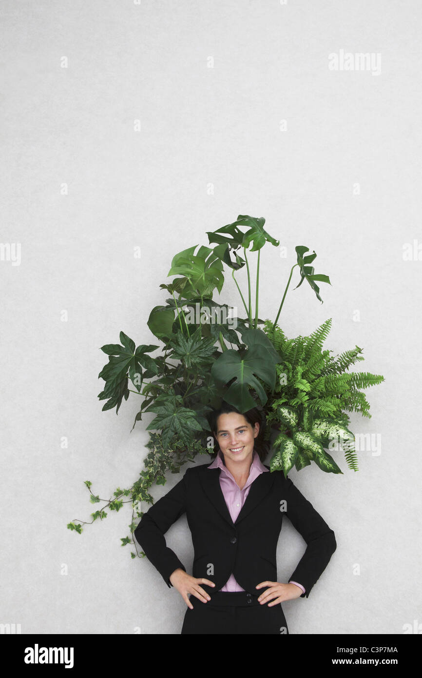 Imprenditrice con foglie di piante, sorridente, ritratto, vista in elevazione Foto Stock