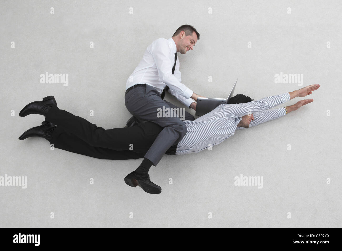 Due imprenditori, uno di loro battenti, l'altra seduta sul suo retro, vista laterale, vista in elevazione, ritratto Foto Stock