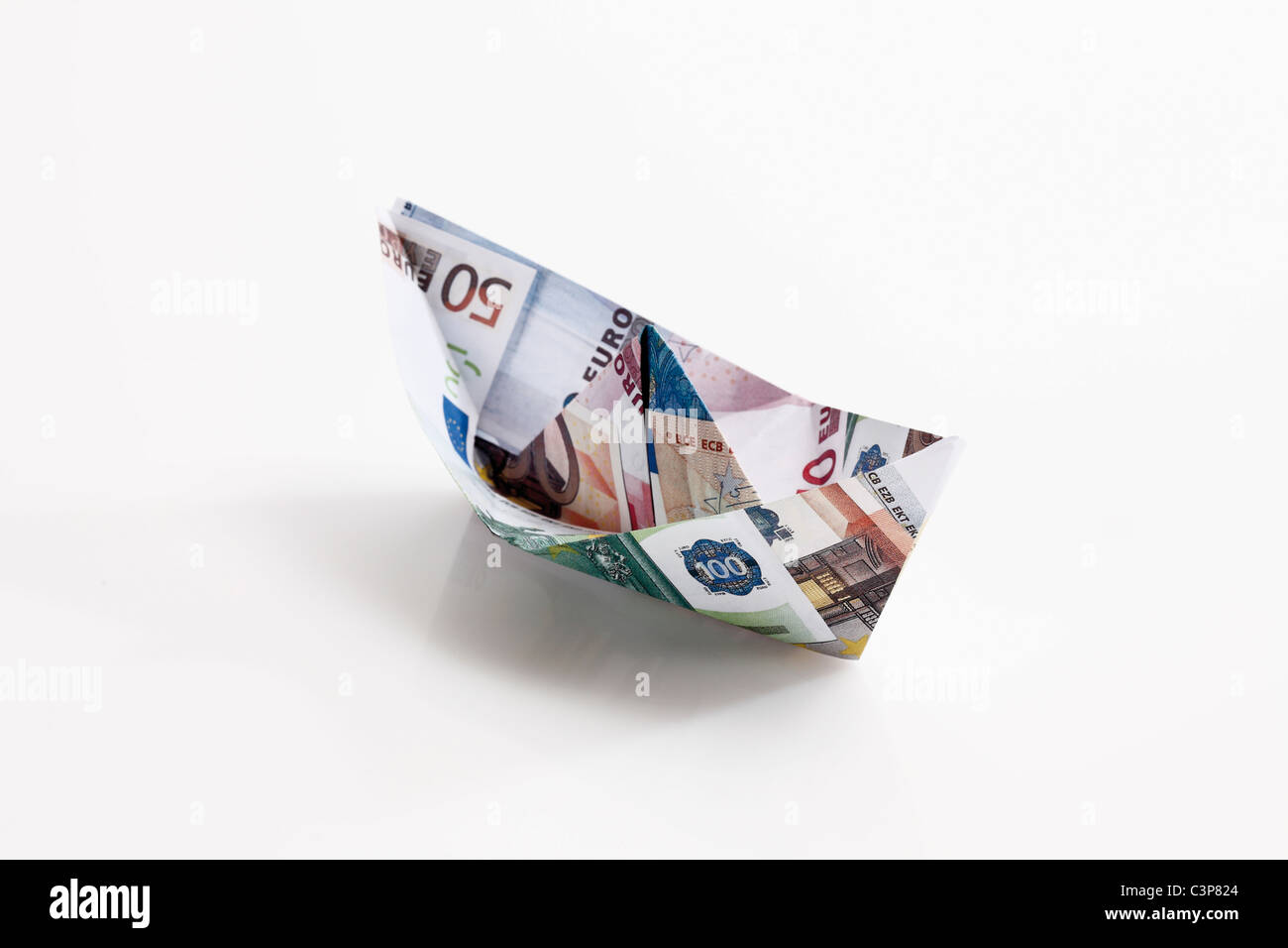 Carta Origami barca di banconote su sfondo bianco Foto Stock