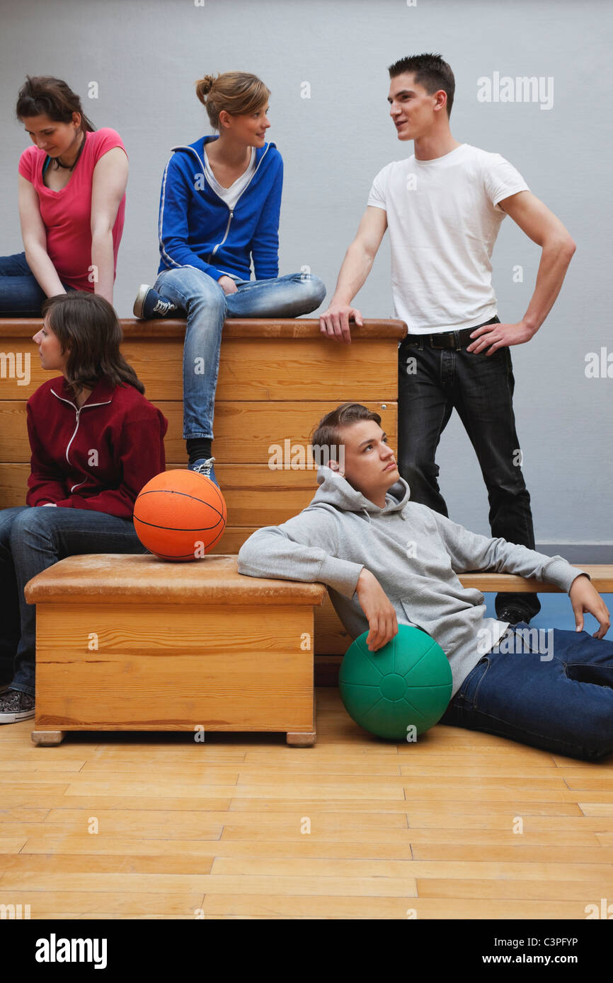 Germania, Berlino, giovani uomini e giovani donne sedute in palestra della scuola Foto Stock