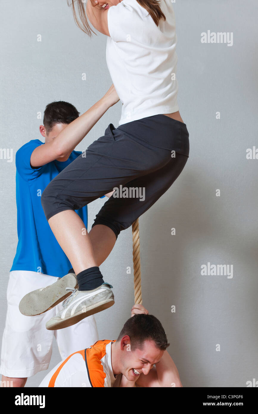 Germania, Berlino, giovani uomini e donne arrampicata corda nella palestra della scuola Foto Stock