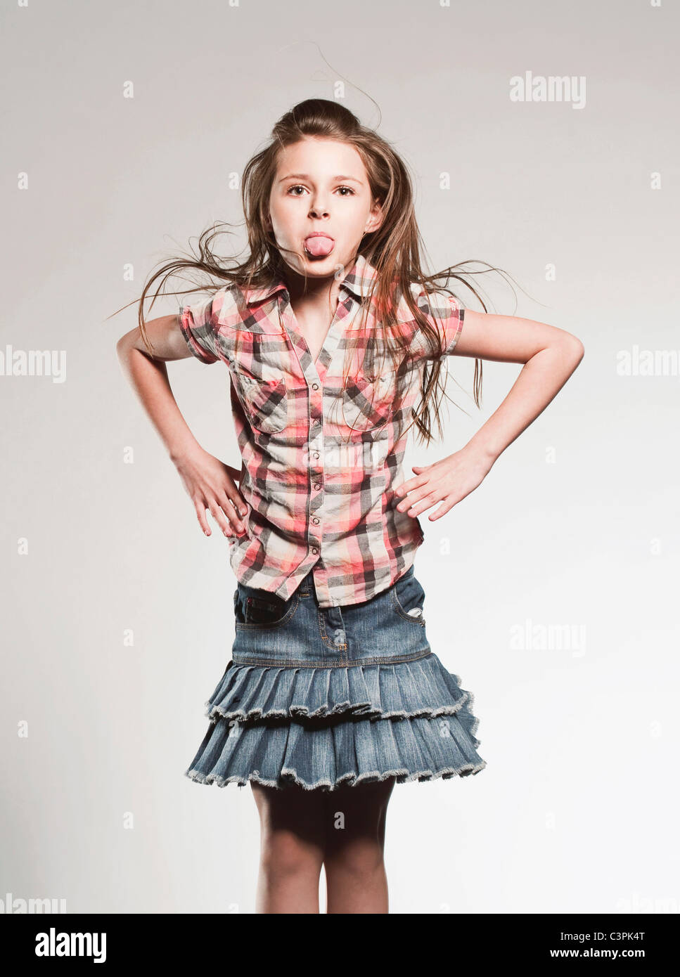 La ragazza (8-9) in piedi con la mano sul hip, spuntavano lingua Foto Stock
