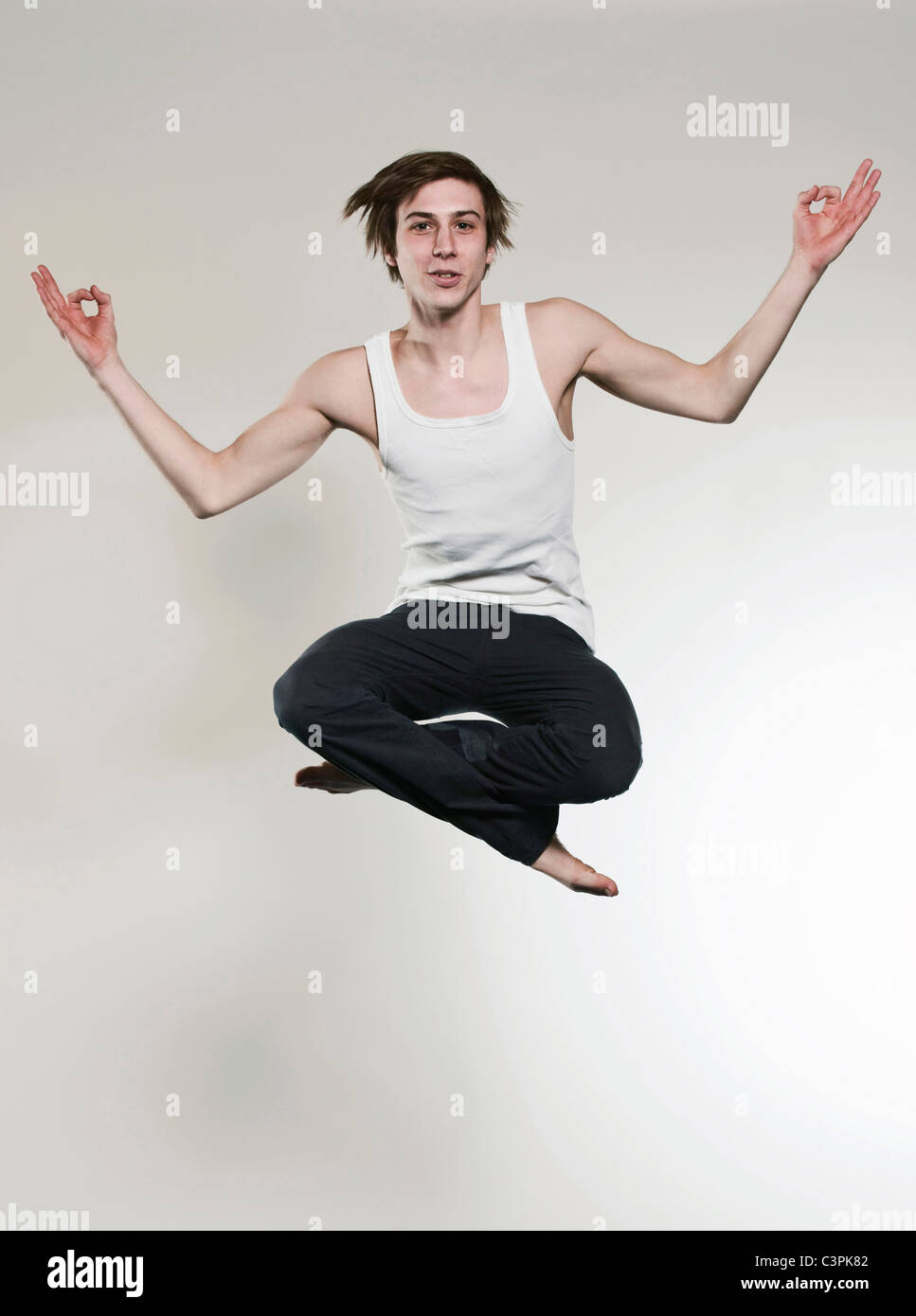 Uomo salta con le gambe incrociate e gesticolando, ritratto Foto Stock