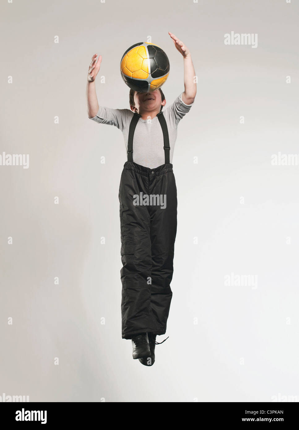 Ragazzo (8-9) jumping con sfera, sorridente Foto Stock