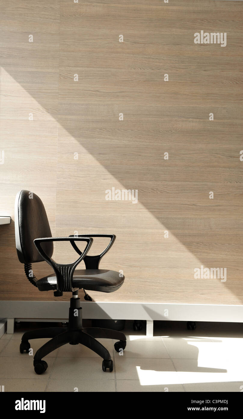 Ritratto di una solitaria sedia ufficio rivolto verso destra. Sfondo di Office. Foto Stock