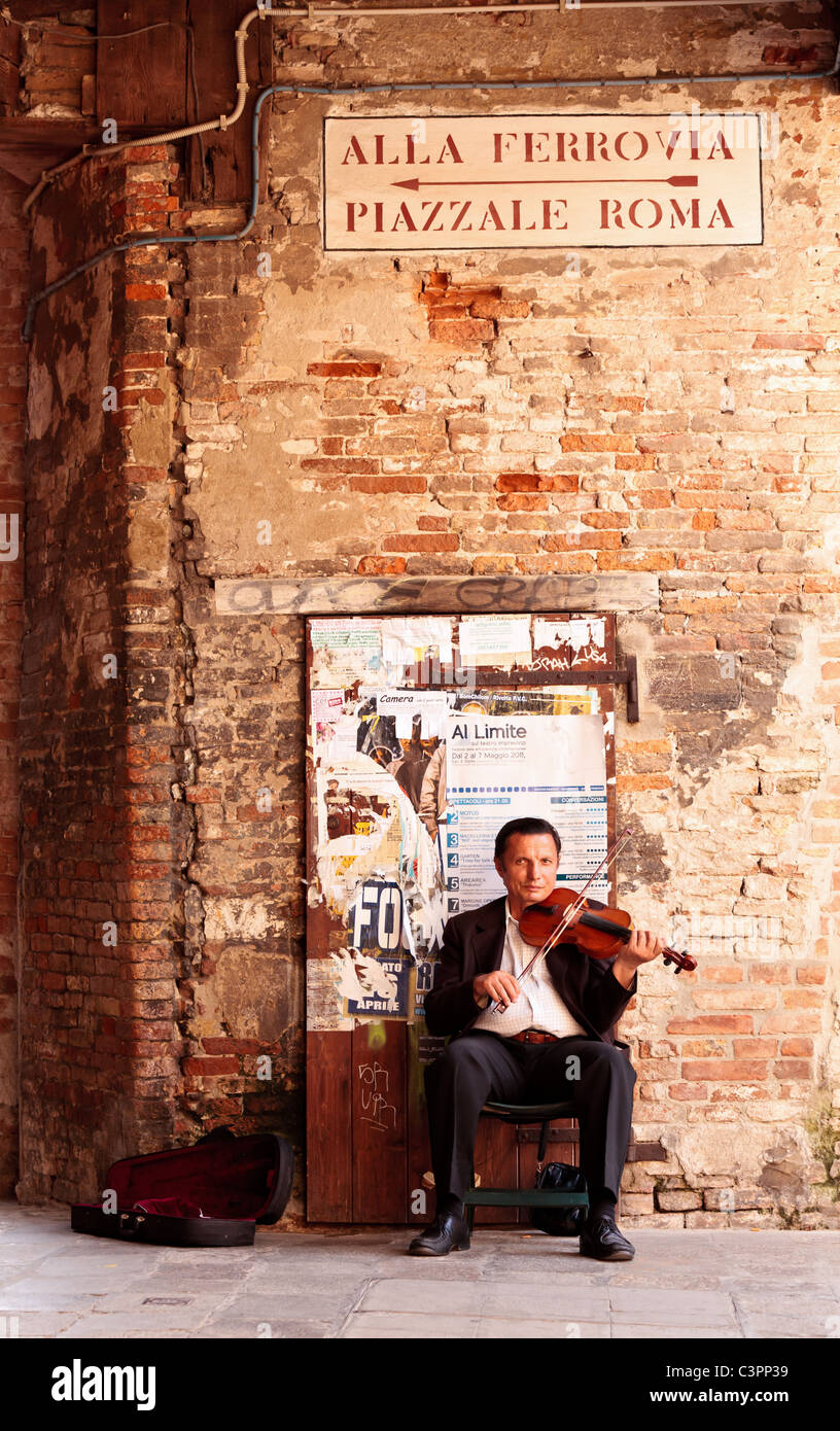 Persone di mezza età busker in tuta la riproduzione di un violino per denaro in Venezia, Veneto, Italia Foto Stock