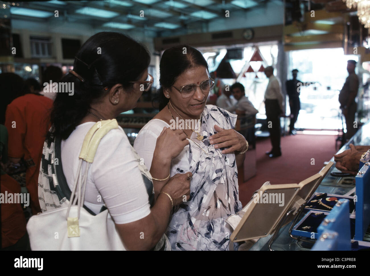 Due donne ispezionare una collana in oro a Nuova Delhi, India gold shop. Foto Stock
