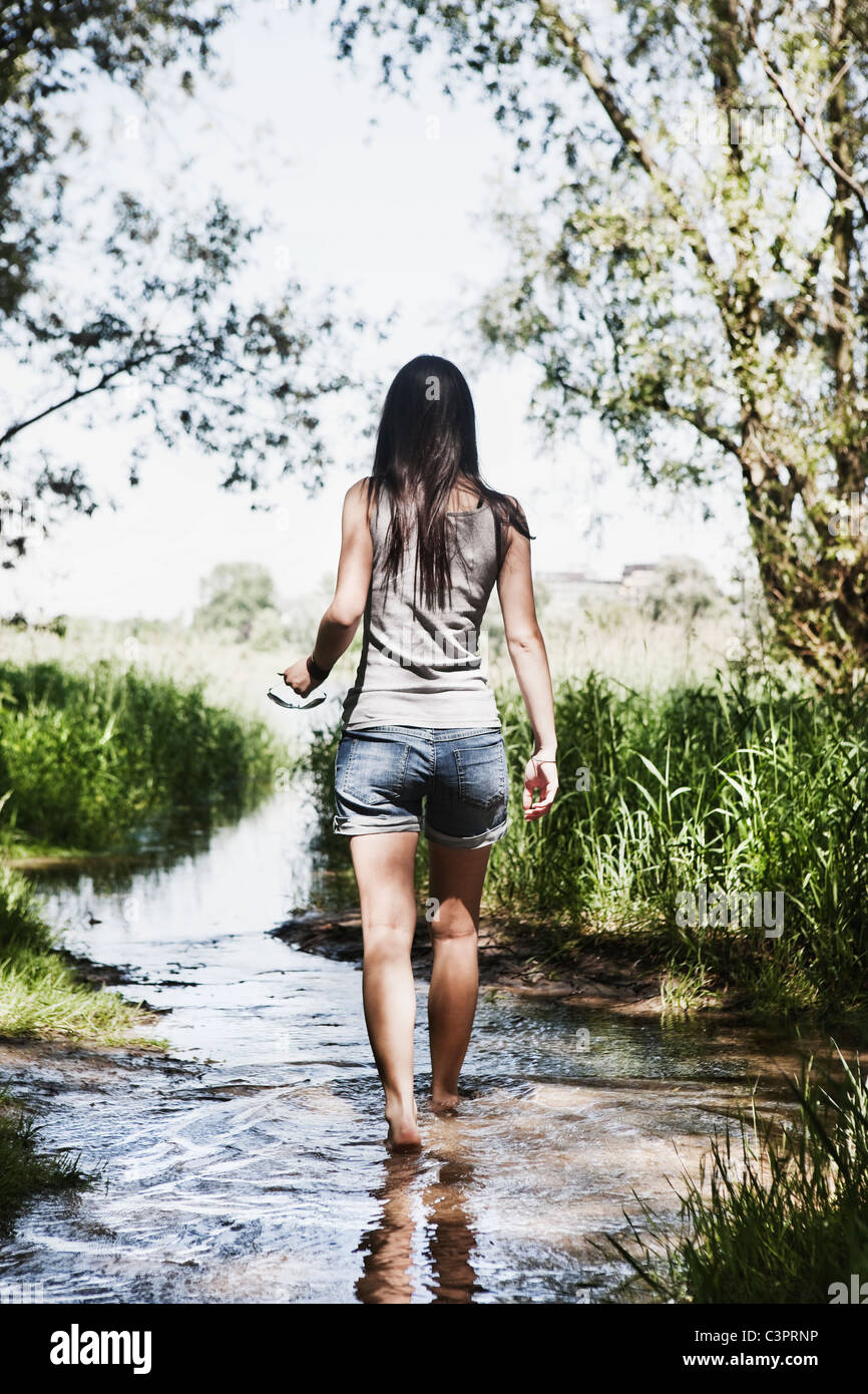 Germania, Colonia, giovane donna camminare in creek Foto Stock