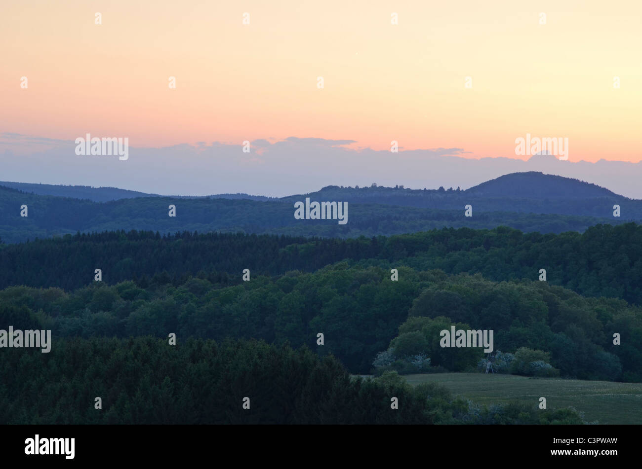 Foresta di legno alberi verdi colline del paese di montagna natura paesaggio naturale moody luce della sera tramonto cielo rosso Germania molla Foto Stock