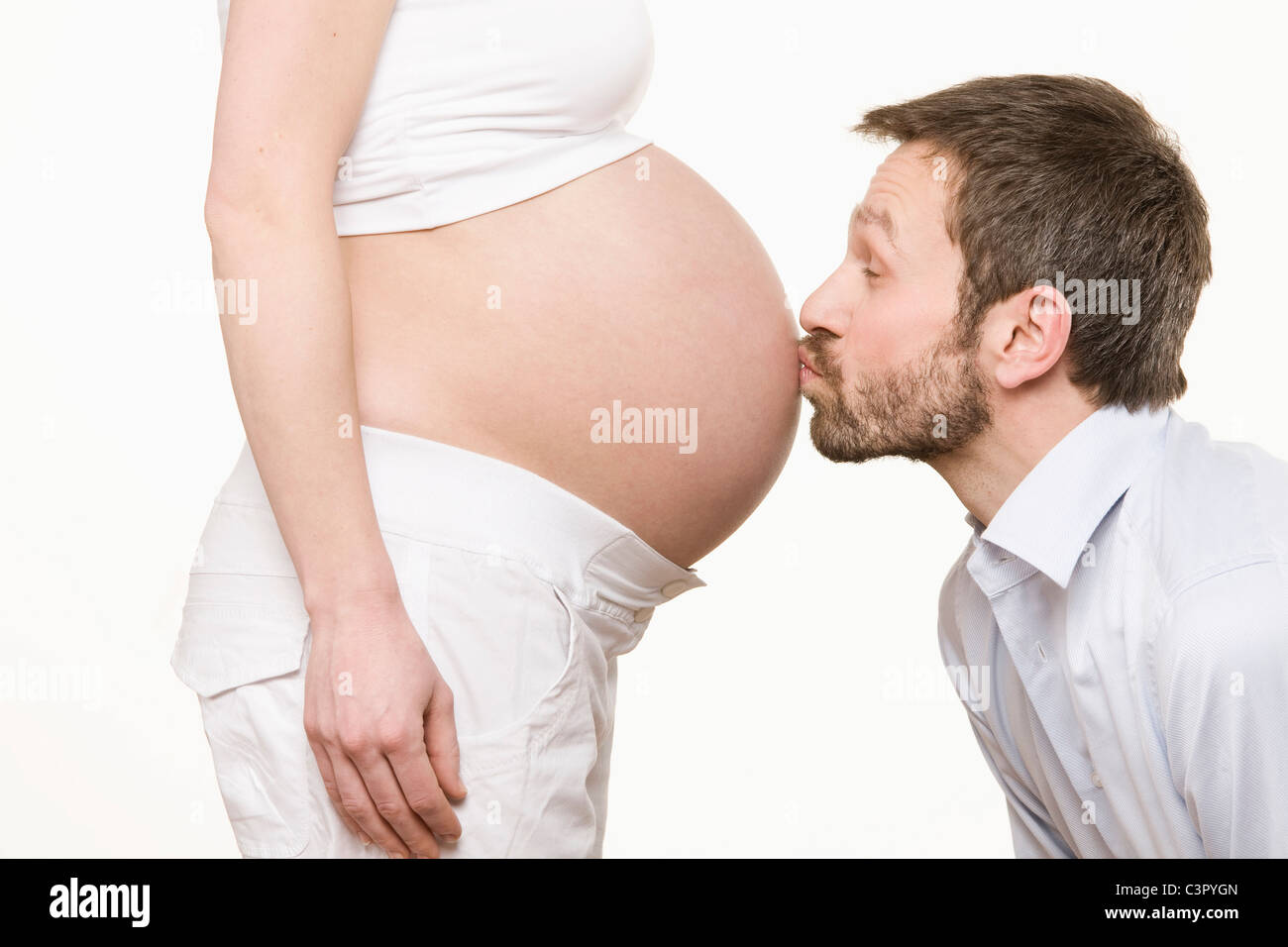 L'uomo il bacio della donna incinta, pancia, vista laterale Foto Stock
