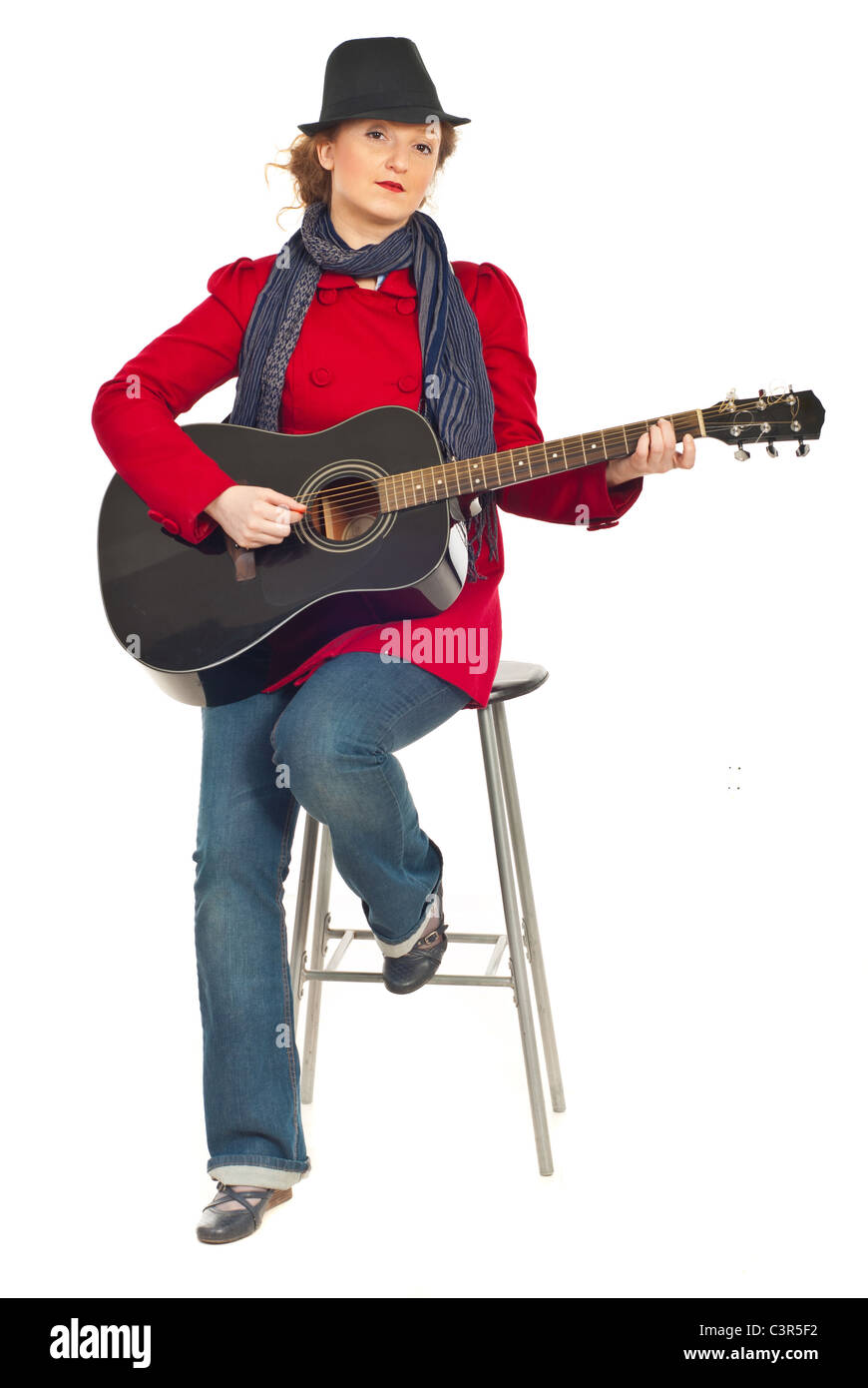 Per tutta la lunghezza della moderna donna seduta su una sedia e suonare la chitarra isolato su sfondo bianco Foto Stock
