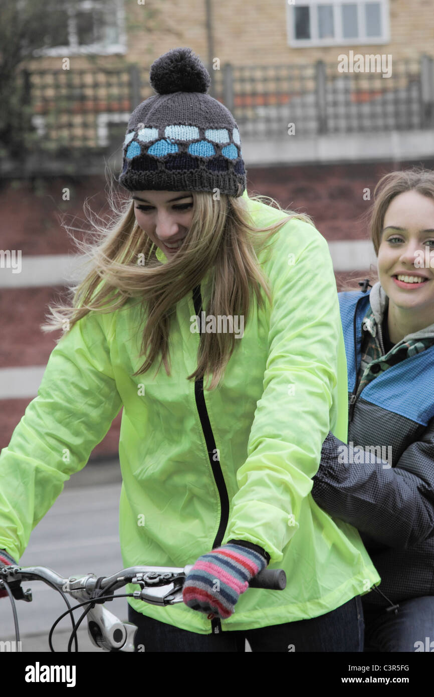 2 giovani donne su 1 spingere bike Foto Stock