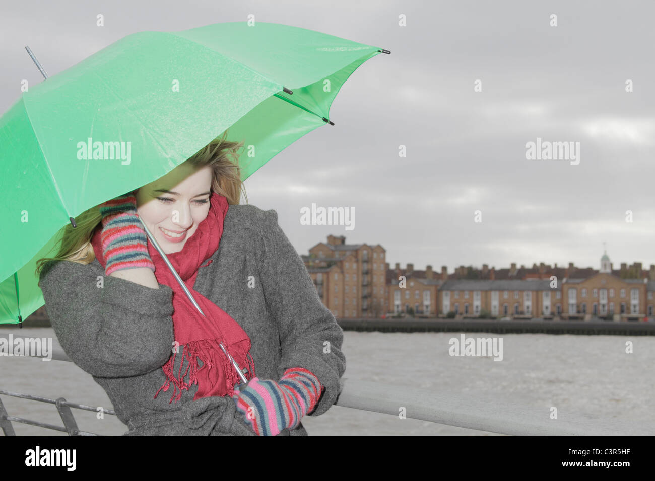 Giovane donna con ombrello verde Foto Stock