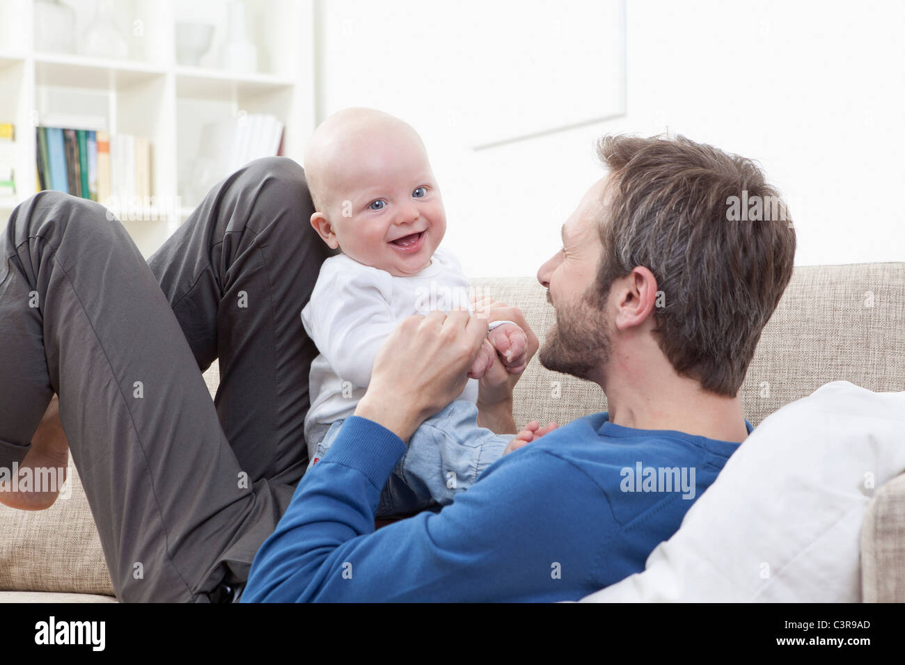 In Germania, in Baviera, Monaco di Baviera, padre e baby boy (6-11 mesi) avendo divertimento sul divano Foto Stock