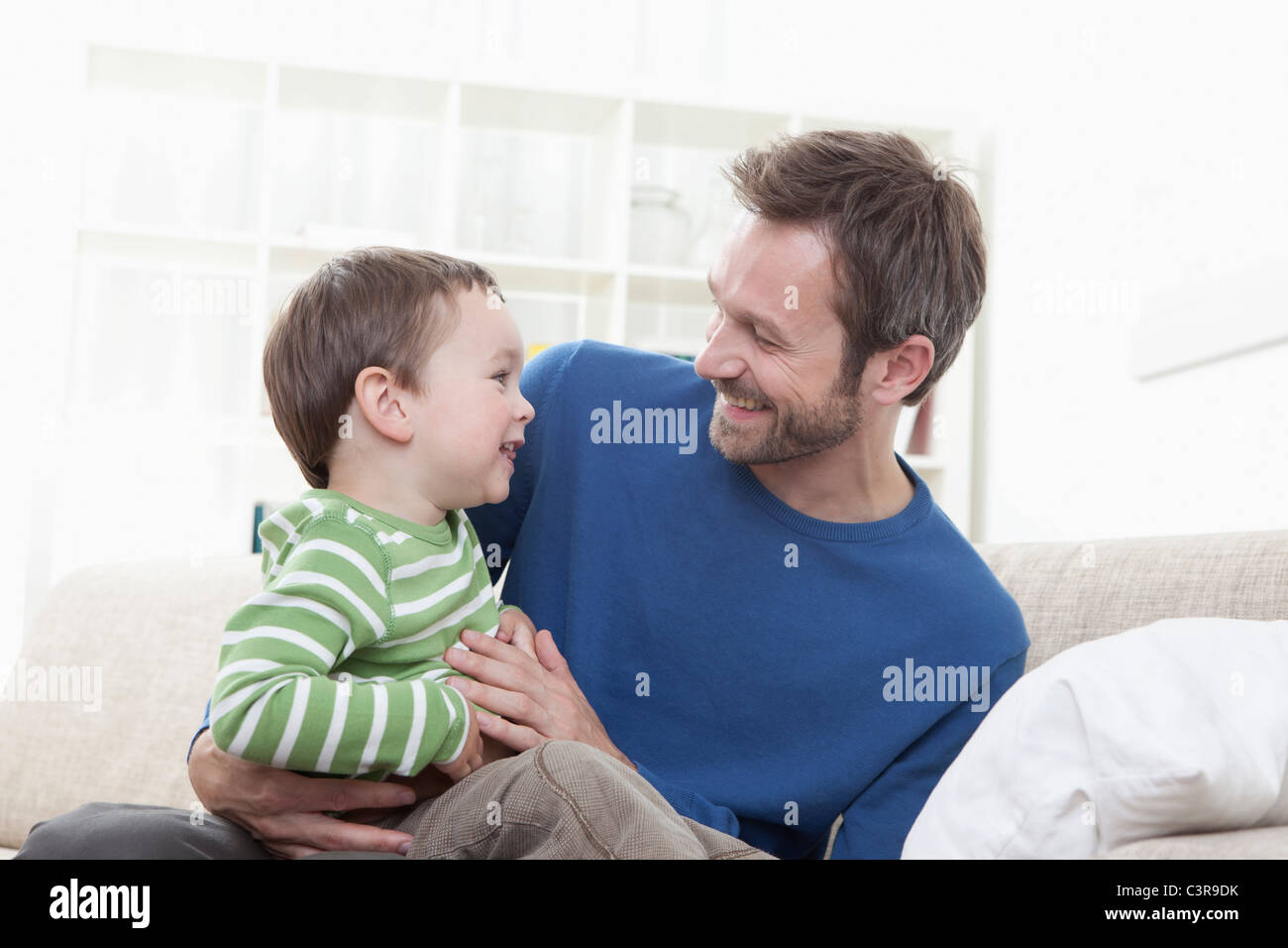 In Germania, in Baviera, Monaco di Baviera, il Padre e il ragazzo (2-3 anni) avendo divertimento sul divano Foto Stock