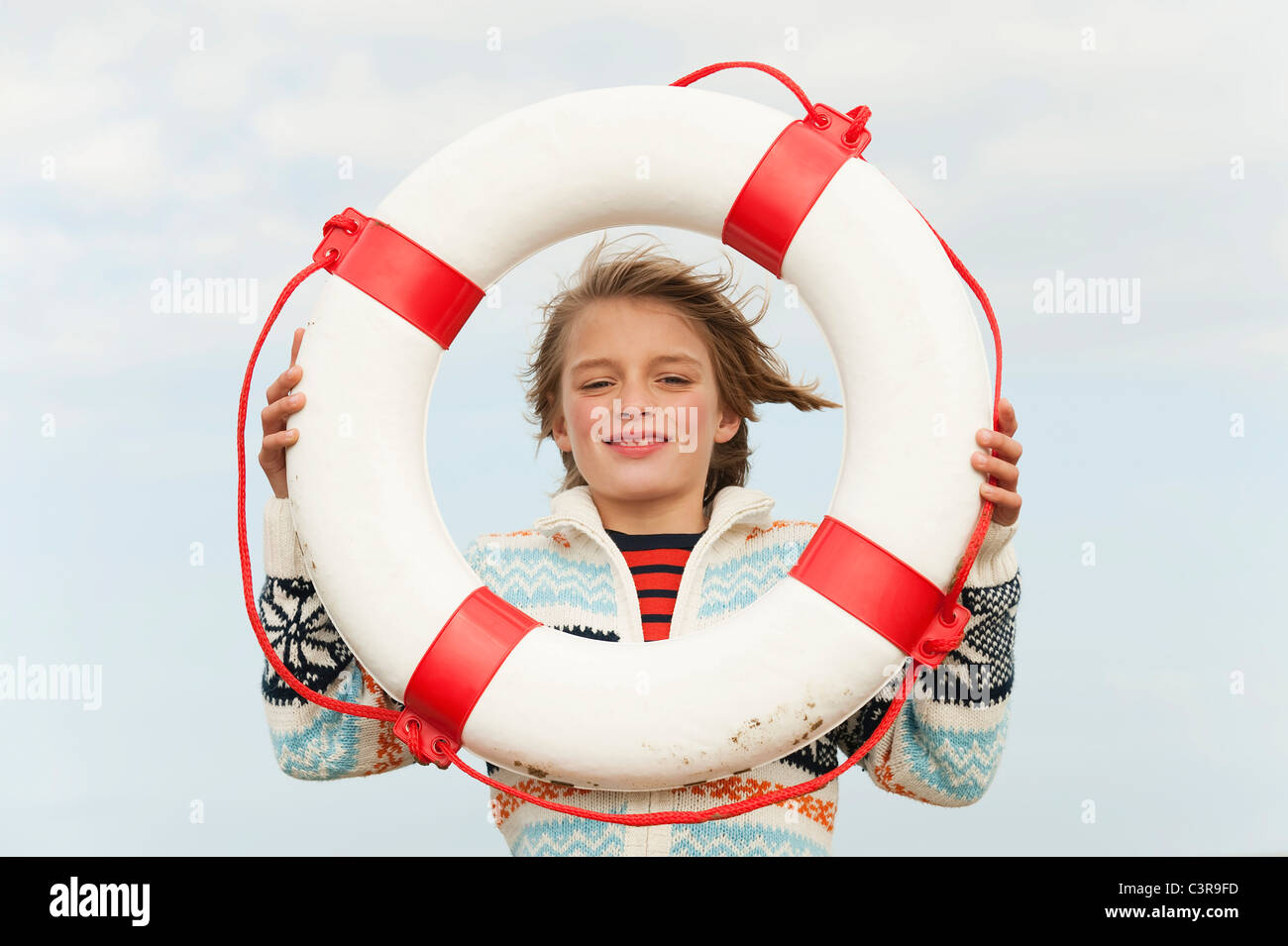 Germania, Mare del Nord, St.Peter-Ording, ragazzo (8-9) azienda life saver a beach, sorridente, ritratto Foto Stock