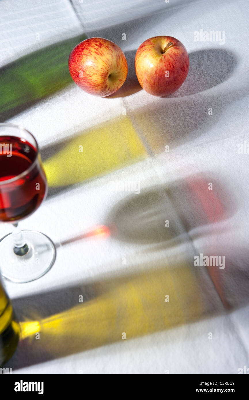 Uno studio in luce: le ombre delle bottiglie di vino con mele e un bicchiere di vino Foto Stock