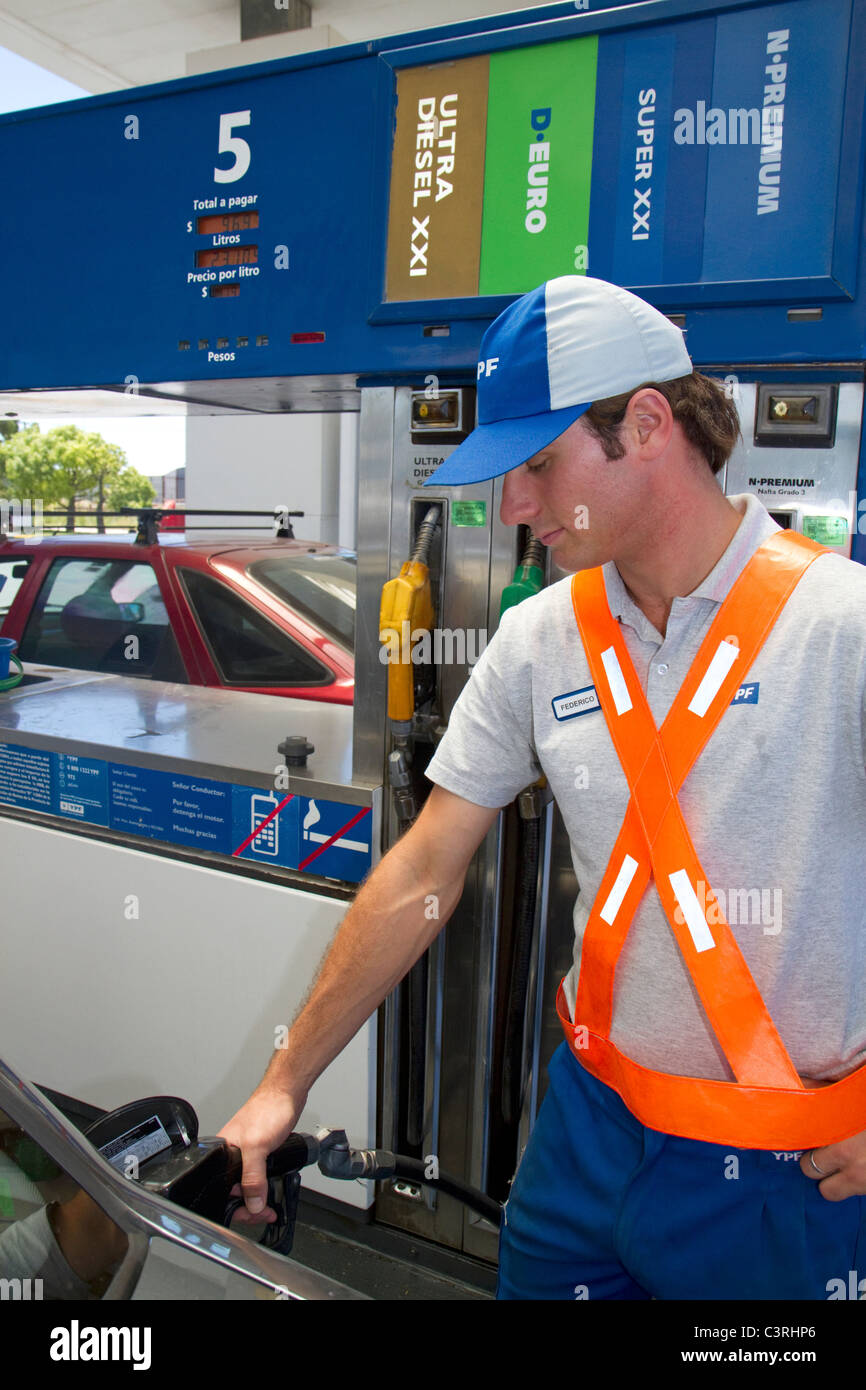 Gas station attendant alimentando un automobile in Argentina. Foto Stock