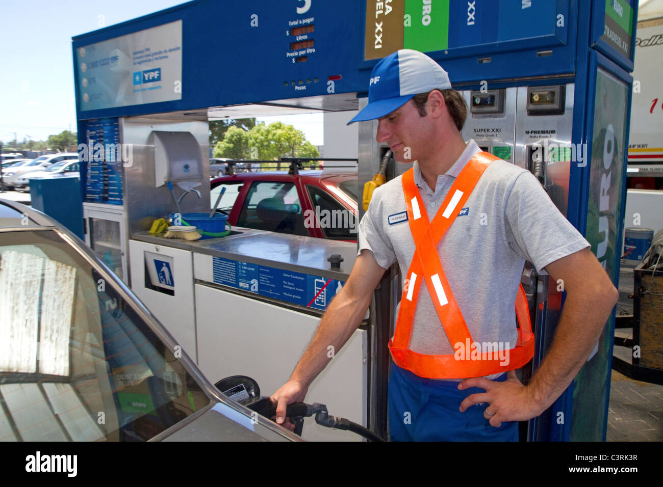 Gas station attendant alimentando un automobile in Argentina. Foto Stock