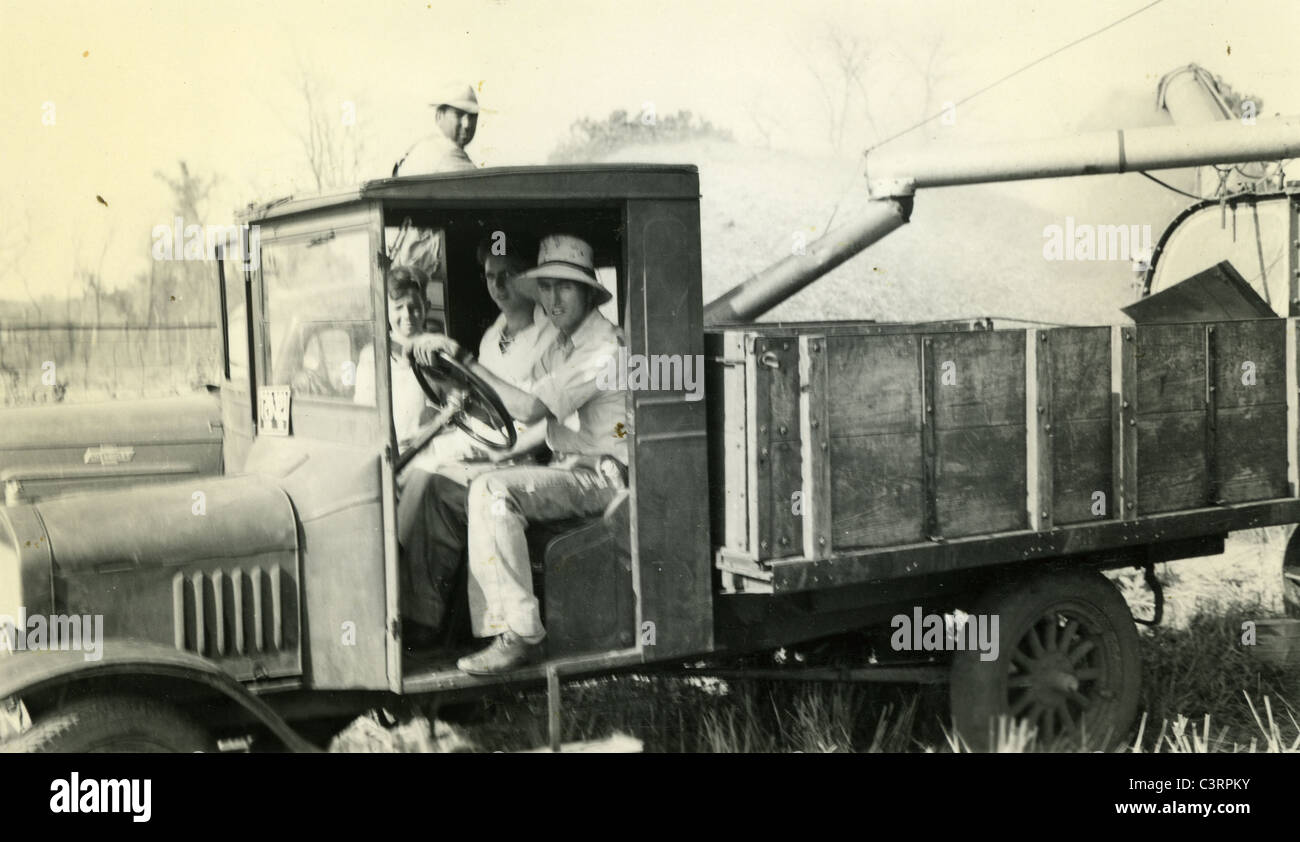Operai agricoli a sedersi in un carrello durante il raccolto di cereali 1930 carrello lavoro lavoratori poveri uomini meccanizzati manuale Foto Stock