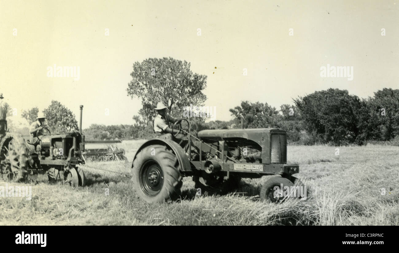 Un maso operaio utilizza ALLIS CHALMERS trattore per tirare un altro nel corso degli anni trenta il raccolto Foto Stock