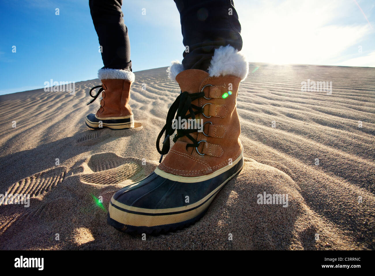 Persona che indossa scarponi in piedi nella sabbia Foto Stock