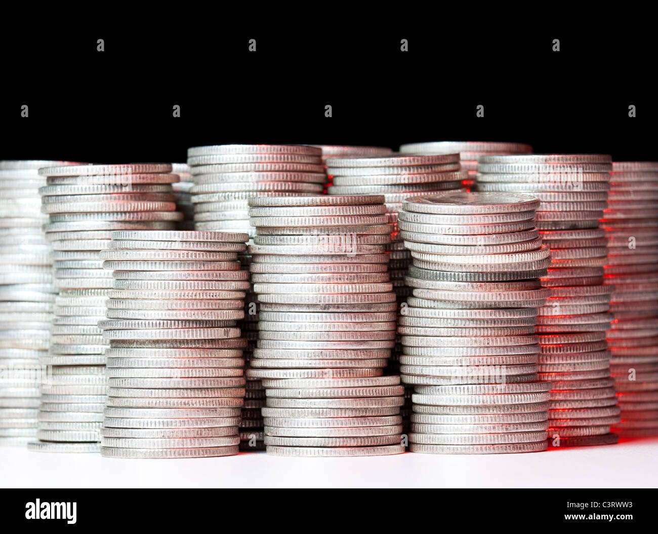 Molte pile di argento vecchio spiccioli di fronte alla telecamera e illuminato con luce rossa Foto Stock