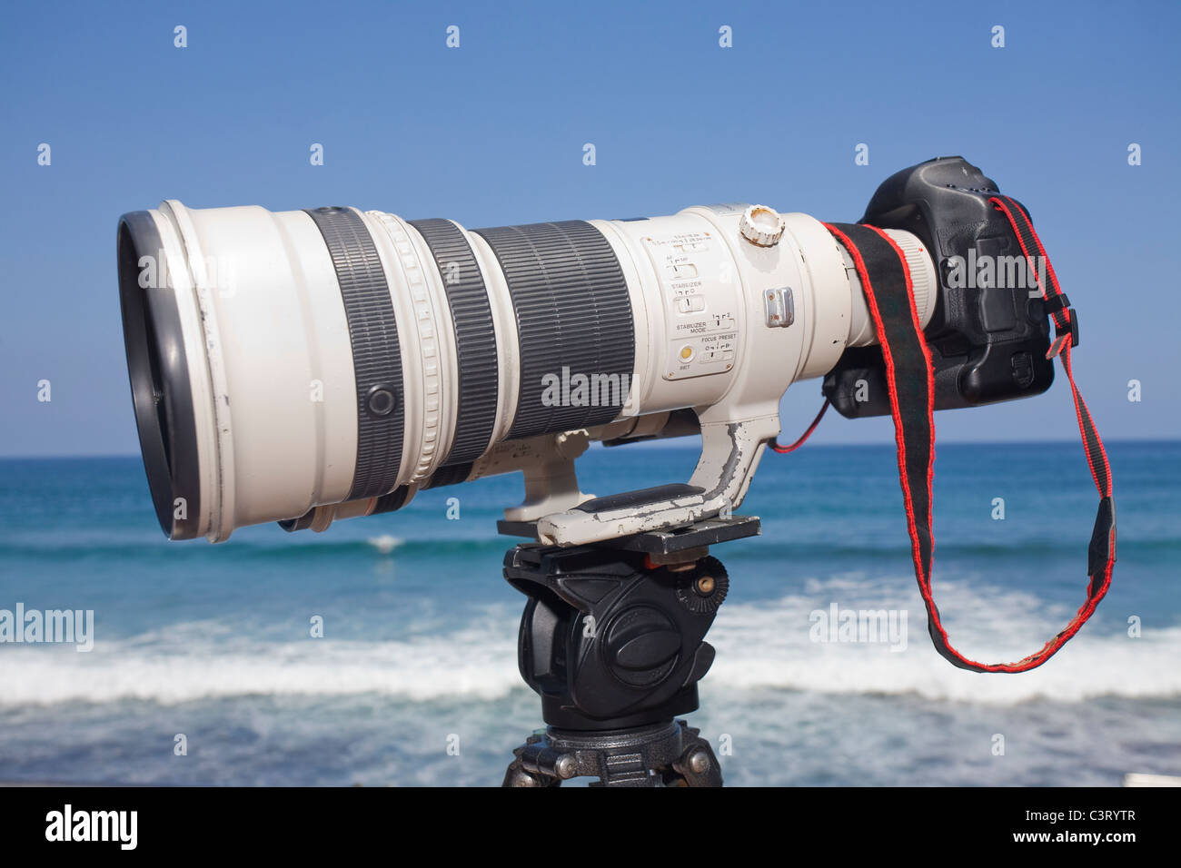 Grande lente di zoom sulla fotocamera DSLR e treppiede a una gara di surf. Foto Stock