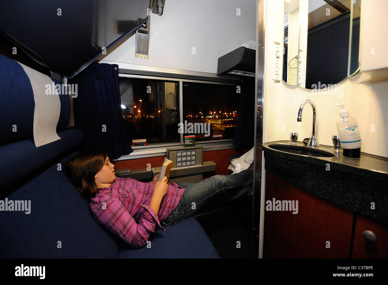 2010. 10 anno vecchia ragazza legge nel suo sonno Amtrak auto per il viaggio da Chicago a Washington DC. Foto Stock