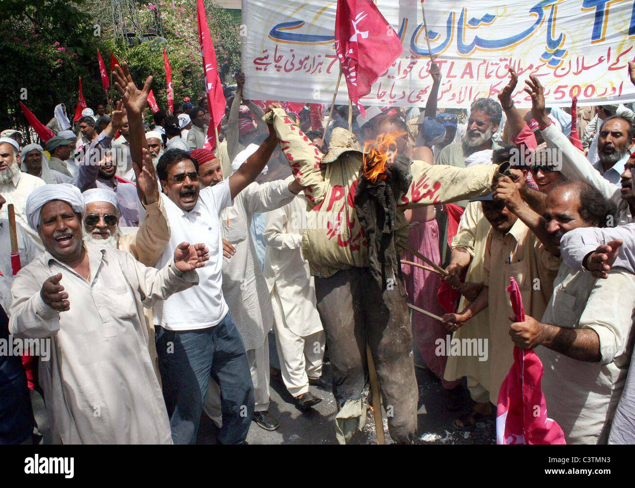 Gli attivisti di ferrovieri Unione masterizzare un'effigie come stanno protestando contro il prezzo-escursionismo a Lahore Foto Stock