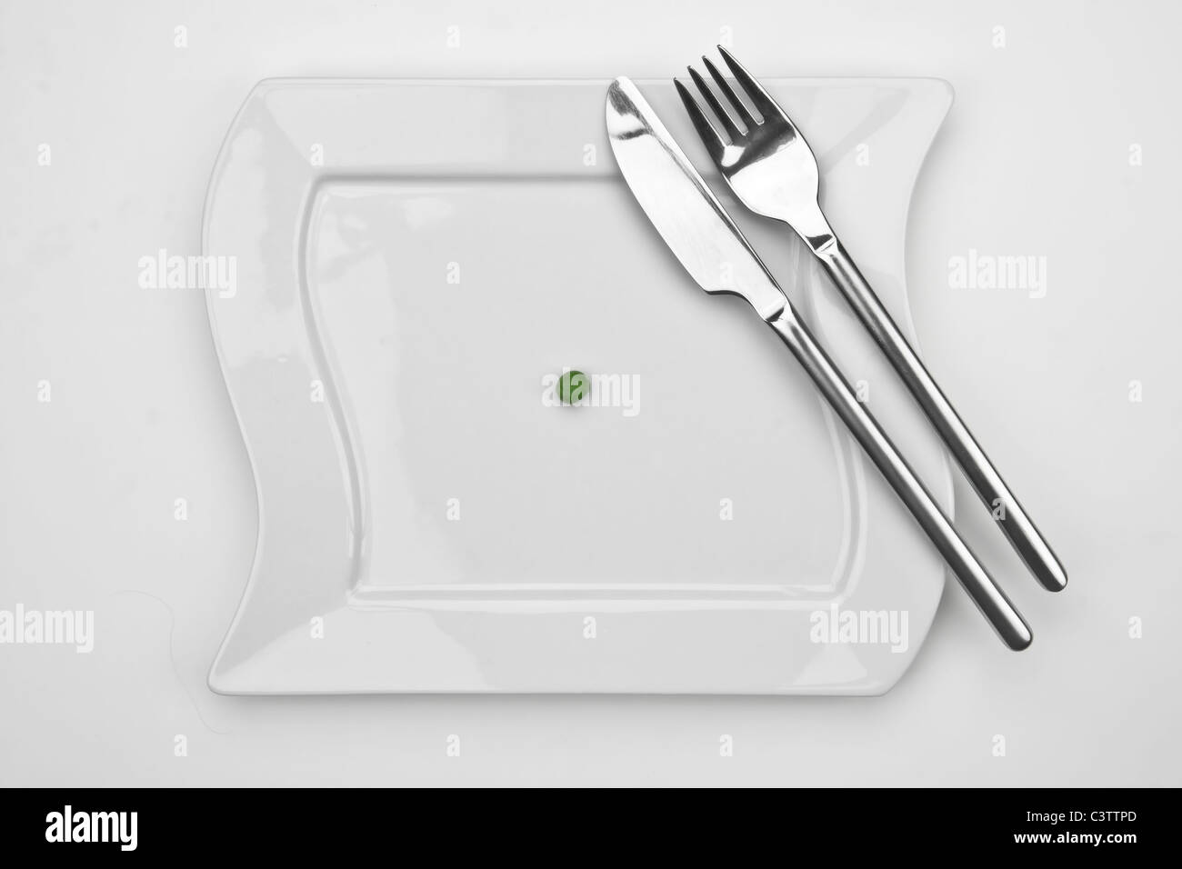 Uno il segnale di PEA su una piastra bianca con la forchetta e coltello Foto Stock