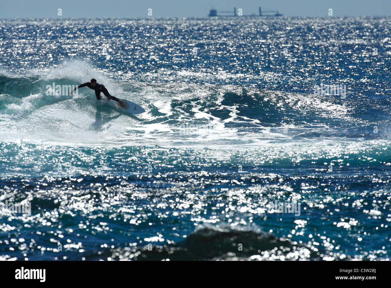 Wave Surfer e nave da carico sull orizzonte Foto Stock