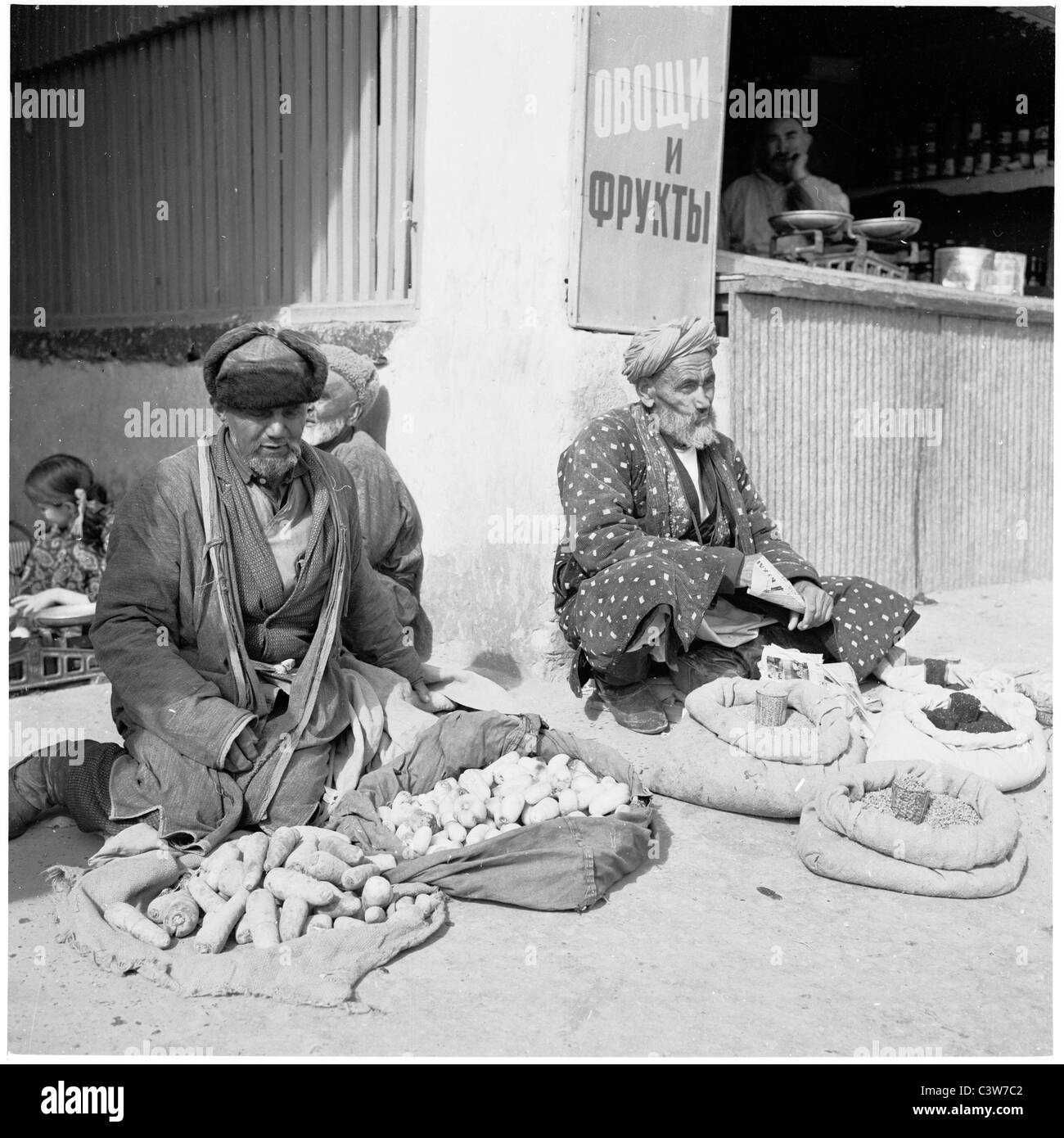 1950s. In questo quadro storico possiamo vedere anziani uzbeki seduta sul terreno la vendita di verdura da sacchi, Bukhara, Uzbekistan. Foto Stock