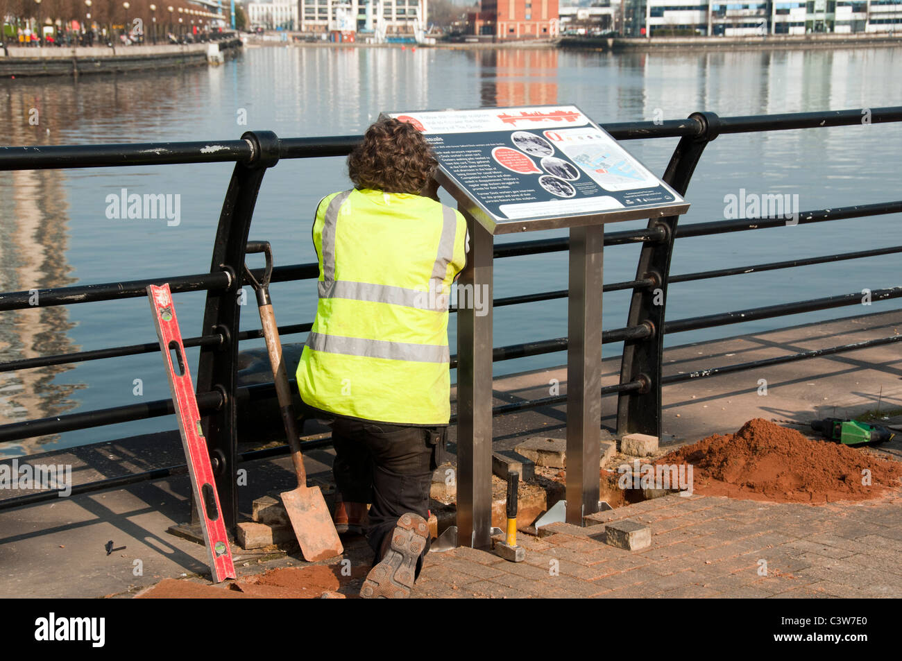 Workman installando una scheda informazioni sullo sblocco di Salford Quays sentiero delle sculture. Salford, Manchester, Inghilterra, Regno Unito Foto Stock