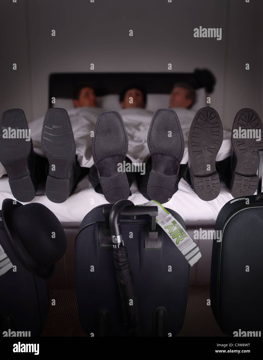 Tre uomini di affari la condivisione di un hotel bed per risparmiare sui viaggi di lavoro Foto Stock