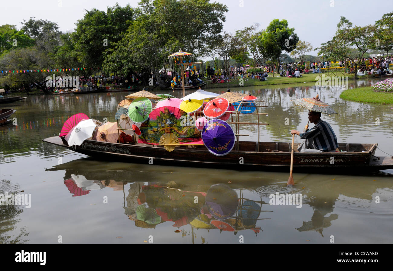 L'uomo vendono ombrelli dalla sua piccola barca, Suan Luang Rama 9 Park, Bangkok, Thailandia Foto Stock