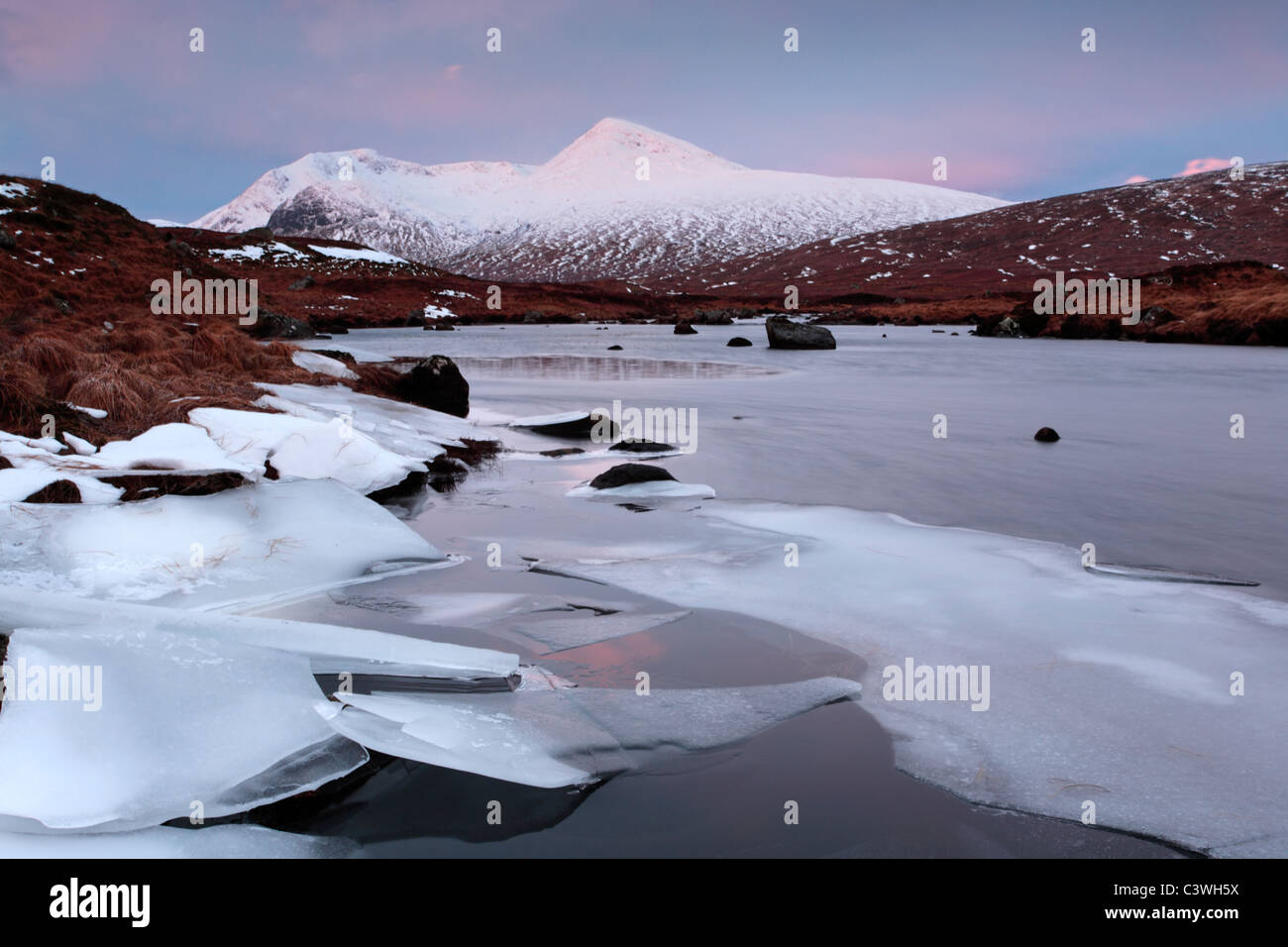 Snow-placcati Meall un Bhuiridh e acque ghiacciate del Lochan na h-Achlaise in Rannoch Moor, Scozia Foto Stock