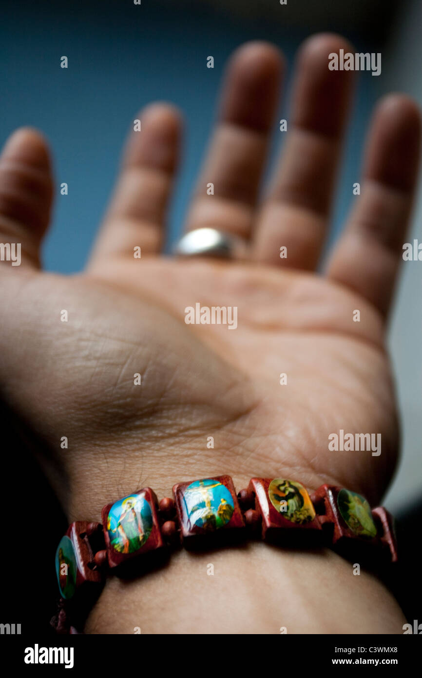 Una mano d'uomo indossa un legno colorato braccialetto religiosa Foto Stock