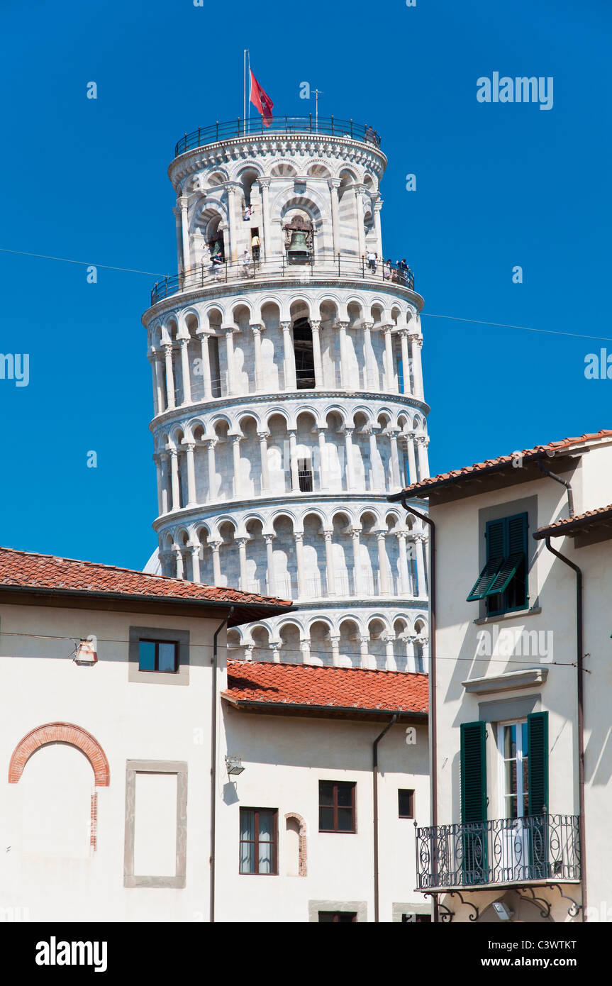 La famosa Torre Pendente in piedi contro il cielo dietro gli edifici del centro della città di Pisa, Toscana, Italia Foto Stock