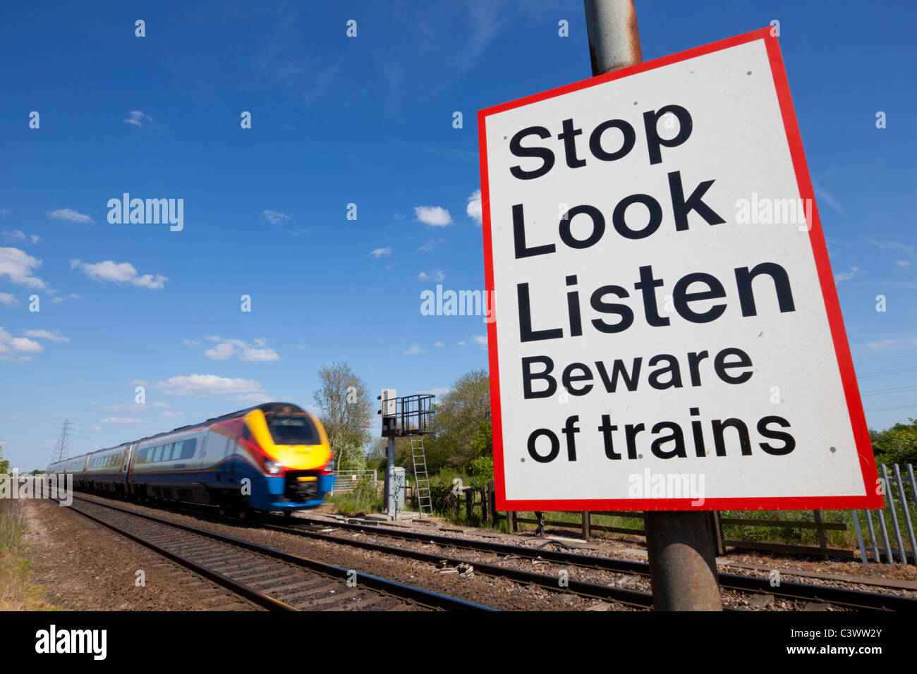 Smettere di guardare ascoltare attenti di treni firmare da un treno in movimento passando un incrocio ferroviario cartello segnaletico Inghilterra GB UK Europa Foto Stock