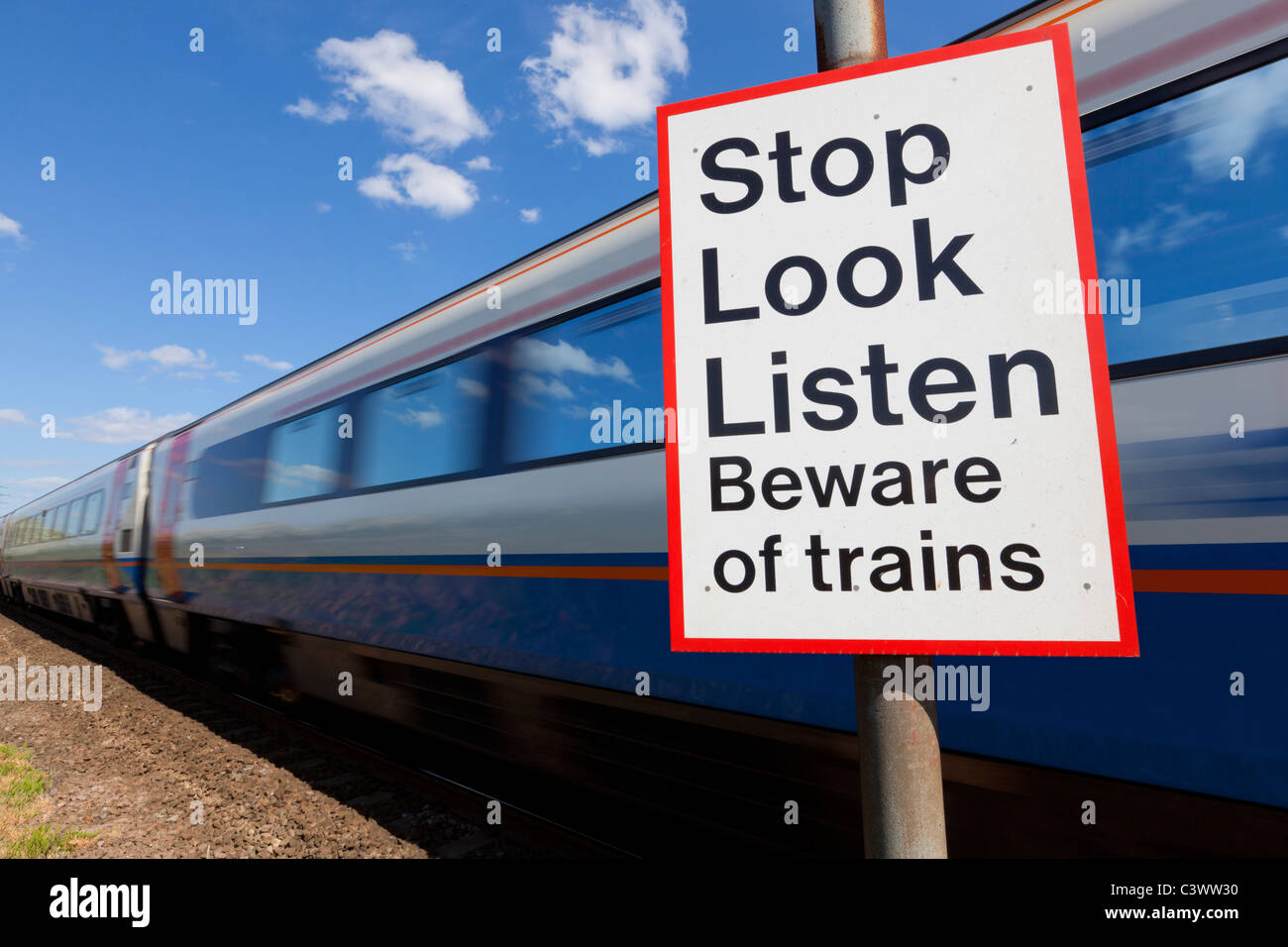 Smettere di guardare ascoltare attenti di treni firmare da un treno in movimento passando un incrocio ferroviario cartello segnaletico Inghilterra GB UK Europa Foto Stock