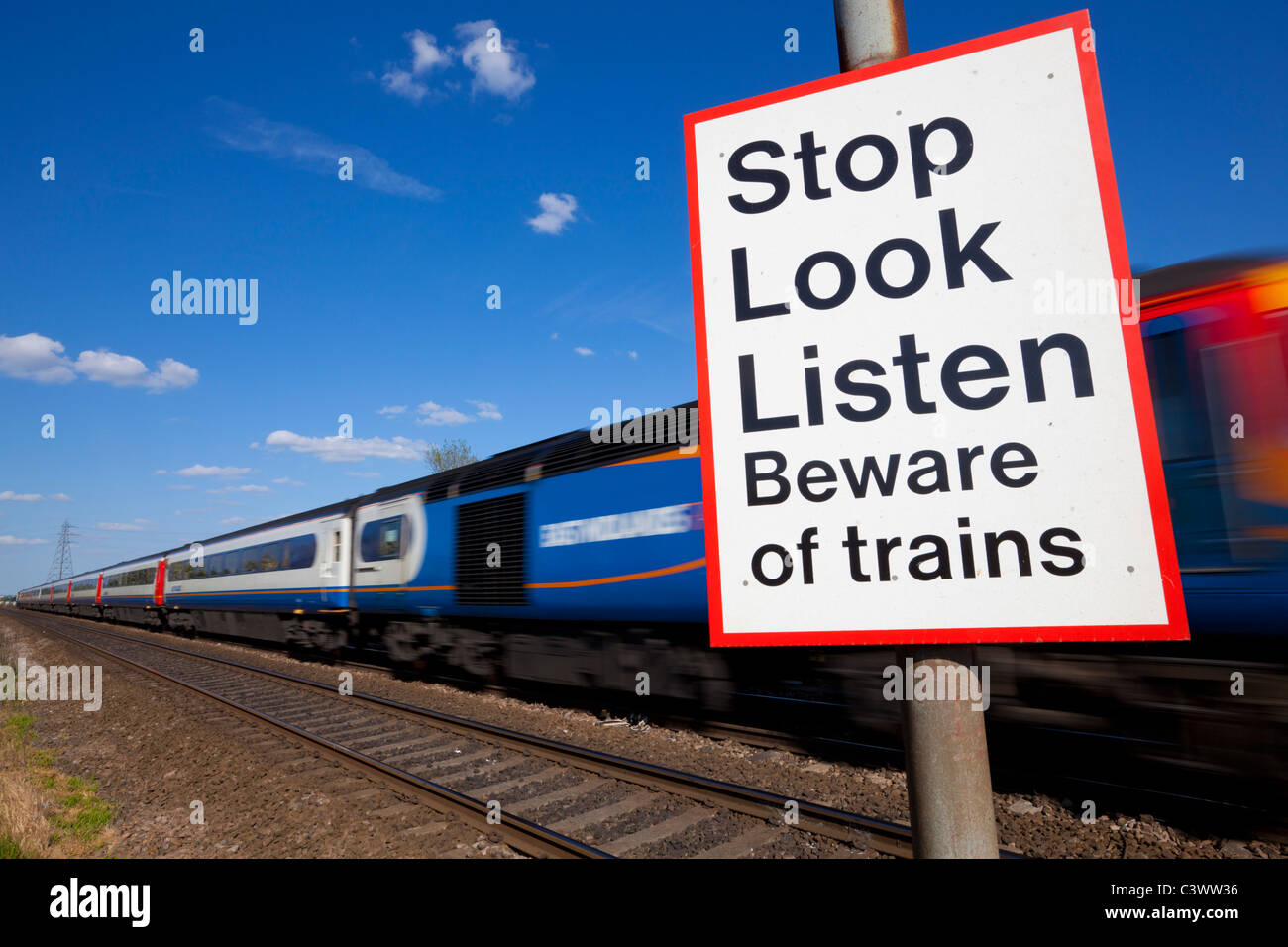 Smettere di guardare ascoltare attenti di treni firmare da un treno in movimento passando un incrocio ferroviario cartello segnaletico Inghilterra GB UK Europa Foto Stock