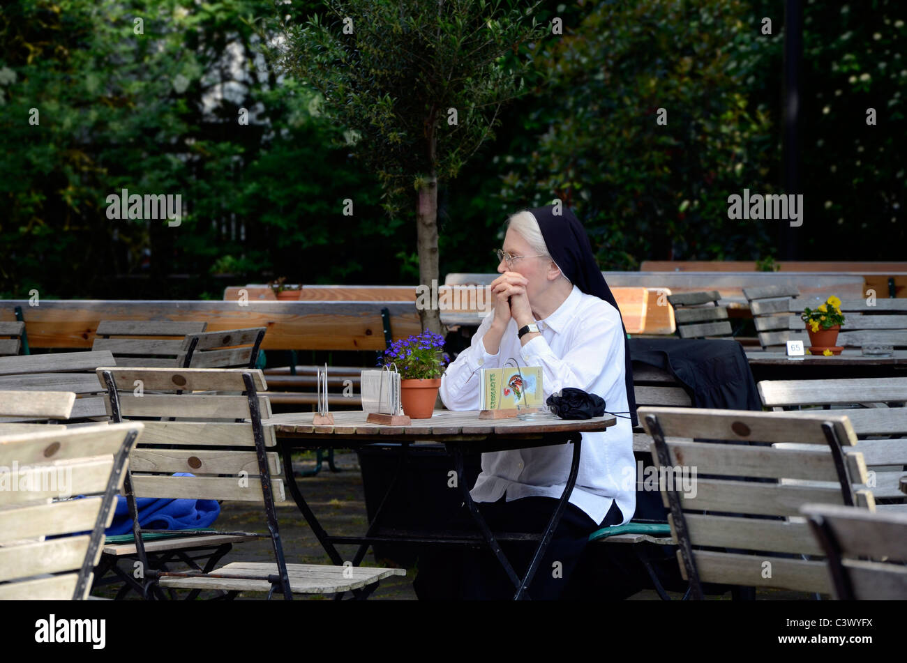 Nun sorella pregare beer garden cafe terrazza fuori abitudine estiva ristorante attesa da sola giornata soleggiata tabella coffeehouse di ghiaccio Foto Stock