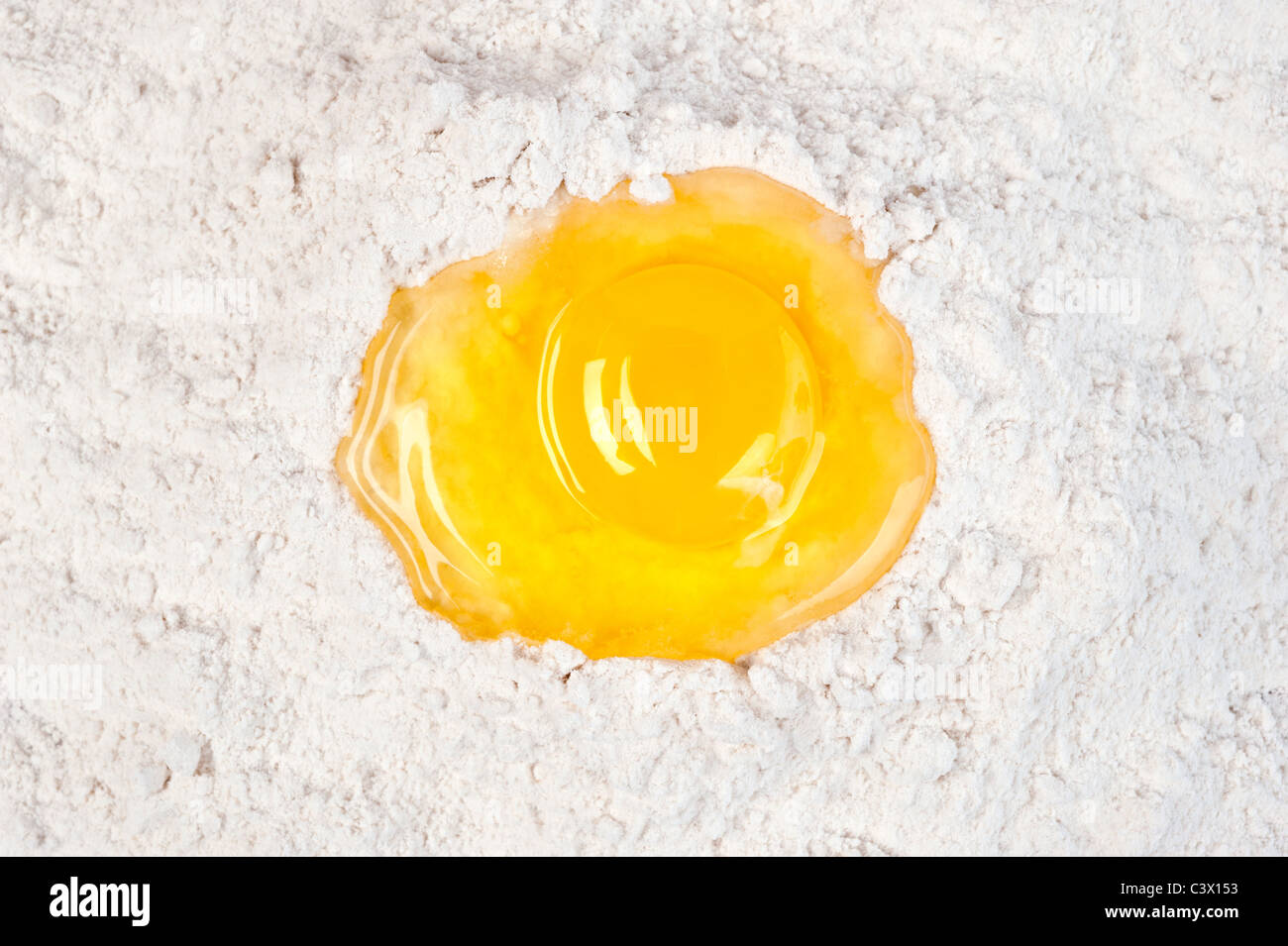 Un solo tuorlo d'uovo in un letto di farina di cottura. Foto Stock