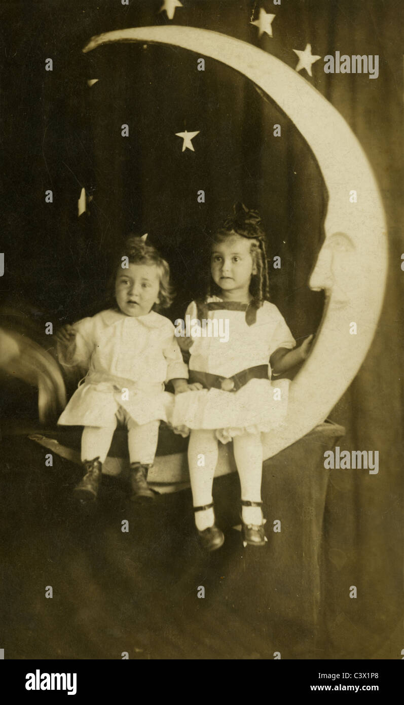 Circa 1910 fotografia di un giovane ragazzo e ragazza seduta su di una carta della luna. Studio fotografico. Foto Stock