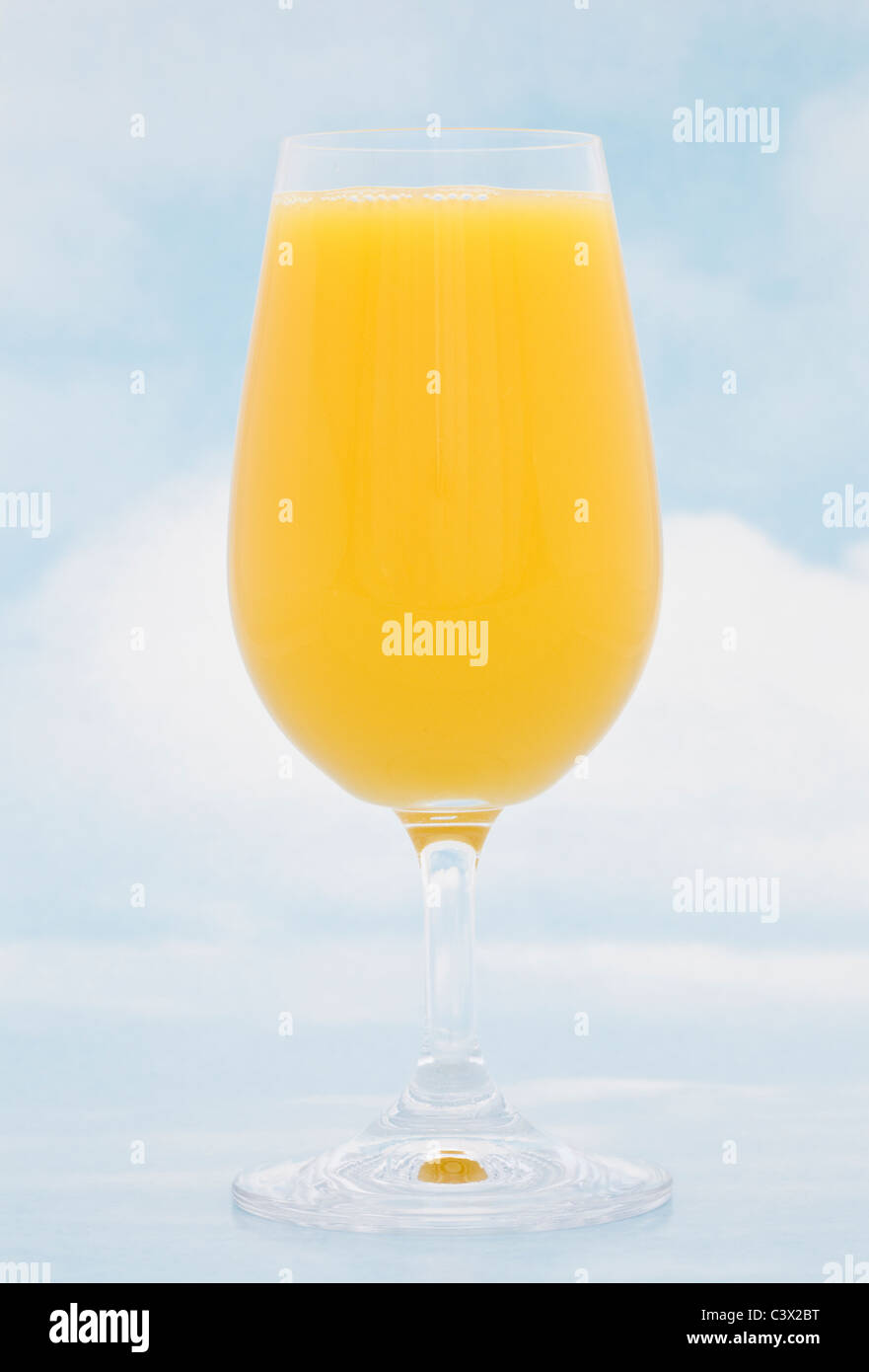 Un bicchiere di succo d'arancia fresco su sfondo blu cielo Foto Stock