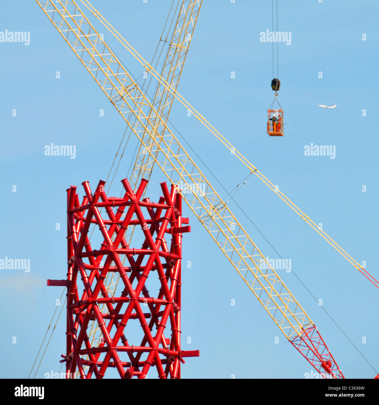 Gru edili incrociata rosso centrale in acciaio strutturale core ArcelorMittal Orbit torre due lavoratori metà aria nella gabbia di accesso Olimpiadi di Londra 2012 REGNO UNITO Foto Stock